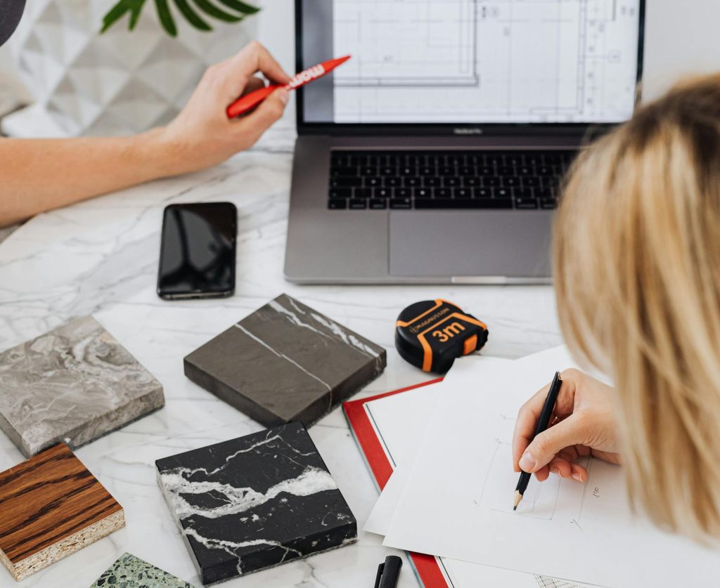 Creative professionals designing interior spaces with laptop and material samples at a modern work table.