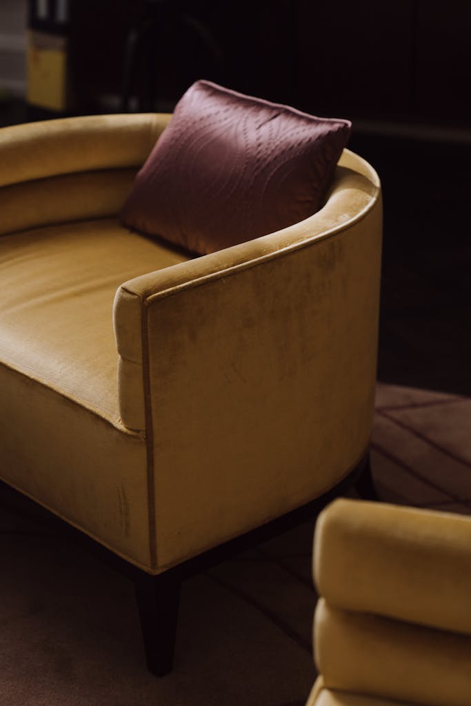 yellow velvet chair with pink pillow cushion in a cozy, stylish indoor setting.